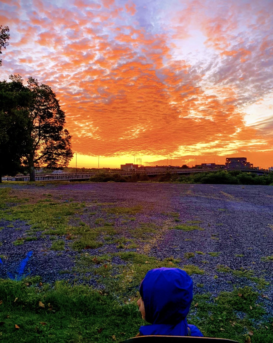 child in jogging stroller in front of sunrise